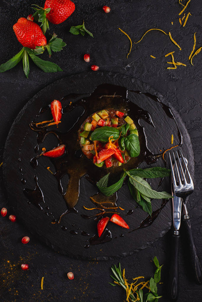 ceviche vegetal com morangos servidos em ardósia sobre fundo preto
 - Foto, Imagem