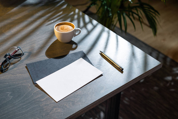 Coffee cup, blank envelopes and glasses and pen on dark wooden table. - Foto, immagini
