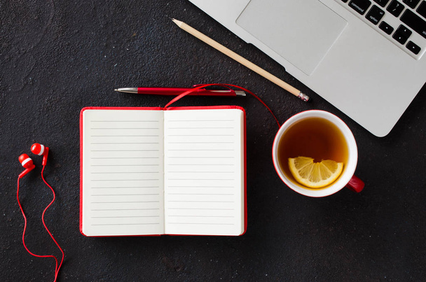 空白の赤いノートブック、コンピュータのラップトップ、ヘッドフォン、紅茶. - 写真・画像