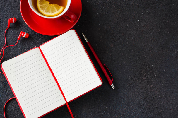 Cuaderno rojo en blanco, computadora portátil, auriculares y una taza de té. Concepto de empresa o educación
. - Foto, Imagen