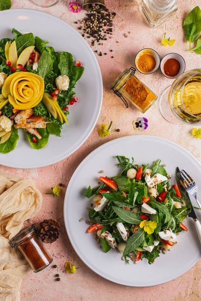 Saladas de legumes frescos servidos em pratos na mesa rosa no restaurante
 - Foto, Imagem
