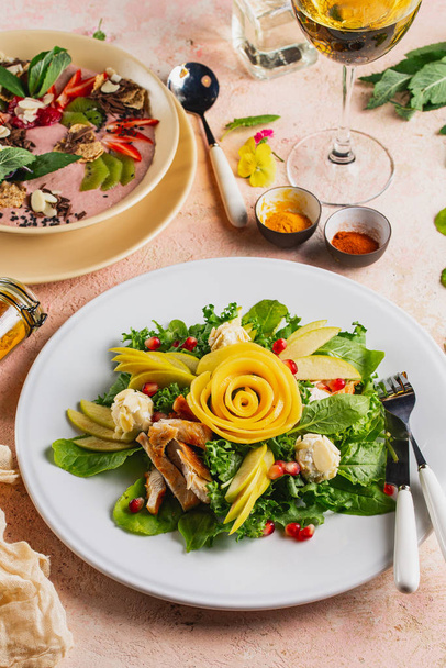 Ensalada de verduras frescas con pechuga de pollo adornada con rosa de fruta tallada servida en plato
 - Foto, imagen
