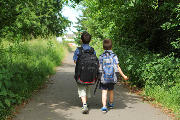 two boys, brothers with school bags go to school on the track, Back to school concept - 写真・画像