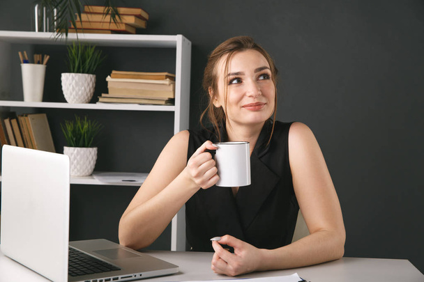 Geschäftsfrau im Büro trinkt Kaffee und arbeitet am Schreibtisch. - Foto, Bild