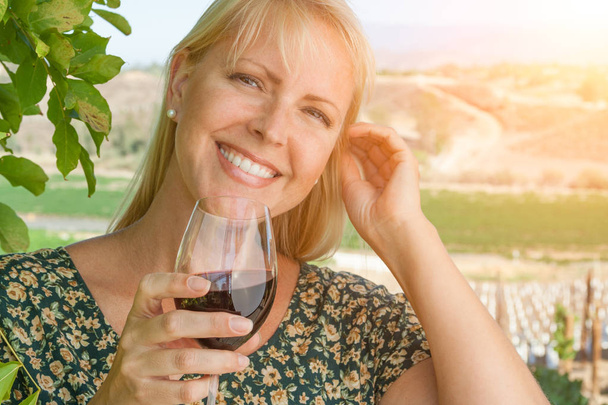 Mulher adulta jovem bonita desfrutando de um copo de degustação de vinhos na vinha
 - Foto, Imagem