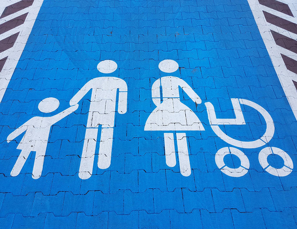 Wegmarkerings teken op een blauwe achtergrond die op parkeren voor een grote familie auto wijst. Het gemak van het parkeren van een voertuig. Reizende ouders en kinderen. Vader met moeder met dochter en zoon - Foto, afbeelding