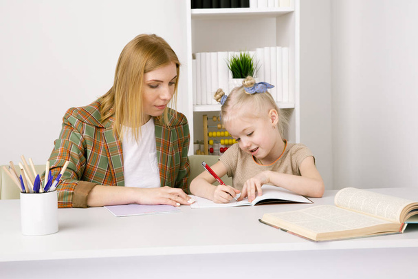 Anne ile evde çalışma masasında birlikte okuyan kız. - Fotoğraf, Görsel
