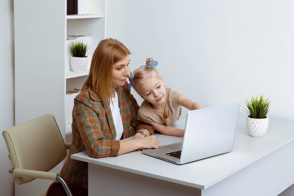 Woman with kid using computer at home together. - Photo, Image