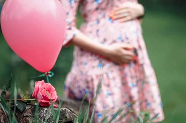 Embarazada mujer tocando golpe mientras sostiene rosa chica esperando
 - Foto, Imagen