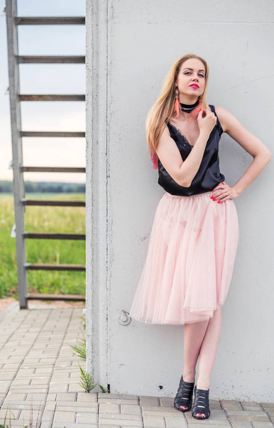 divatos lány modell egy tüll szoknya és fekete Top pózol ellen szürke fal - Fotó, kép
