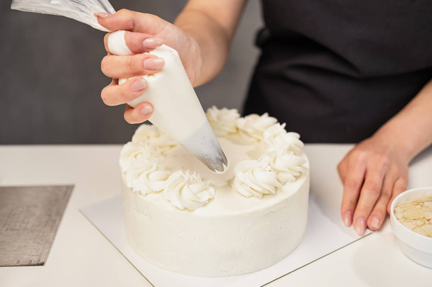 Confectioner at work. Cream cake decorating. Cook table preparing a cake. - Фото, зображення
