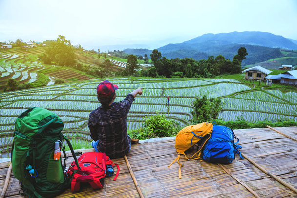 Amante asiático hombre asiático mujeres viaje naturaleza. Caminar una foto del campo de arroz y detener tomar un descanso relajarse en el puente en ban mae klang luang en temporada de lluvias
. - Foto, Imagen