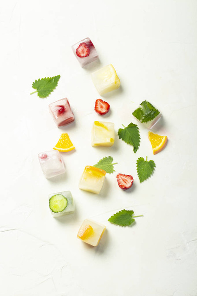 Kostky ledu s ovocem a mátovou listou na bílém kamenném pozadí - Fotografie, Obrázek