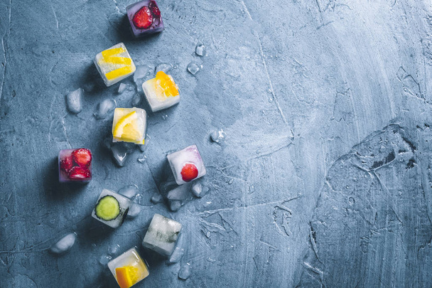 Cubos de hielo con fruta y hielo roto sobre un fondo azul piedra
.  - Foto, imagen