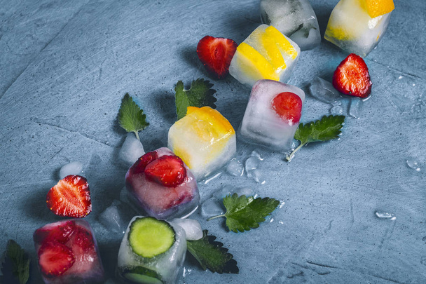 Кубики льда с фруктами и битым льдом на каменном голубом фоне
 - Фото, изображение