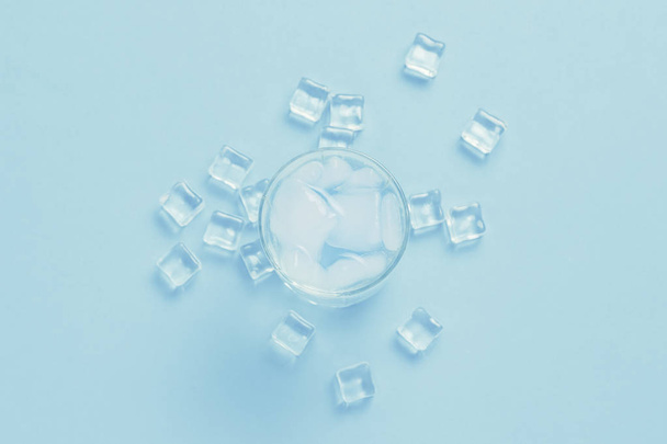 Un vaso de agua fría refrescante con hielo y cubitos de hielo sobre un azul
  - Foto, imagen