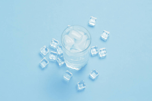 Склянка освіжаючої холодної води з льодом і кубиками льоду на синьому
  - Фото, зображення