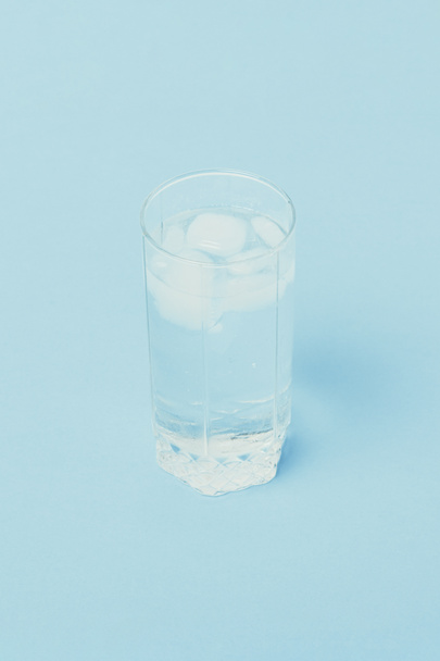 Água fria refrescante com gelo em um copo em um fundo azul
.  - Foto, Imagem