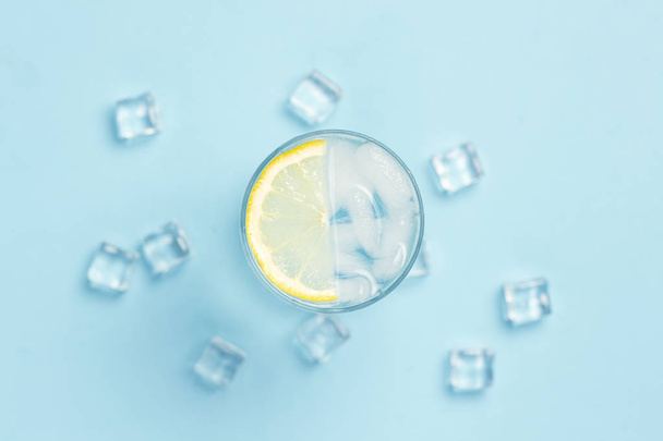 Склянка води або пити з льодом і лимоном на синьому фоні
  - Фото, зображення