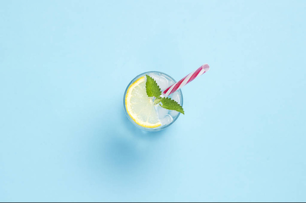 Glass of water or drink with ice, lemon and mint on a blue backg - Photo, image