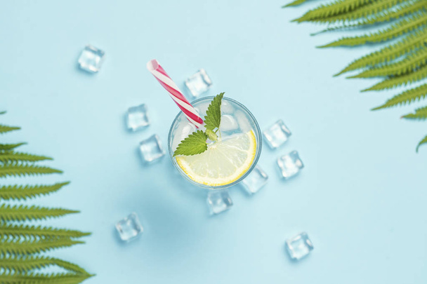 Стакан воды или напиток со льдом, лимоном и мятой на синем фоне
 - Фото, изображение