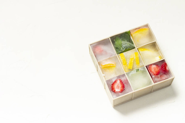 Kostki lodu z owocami w formie silikonowej na białym kamieniu oświetlenie tła - Zdjęcie, obraz
