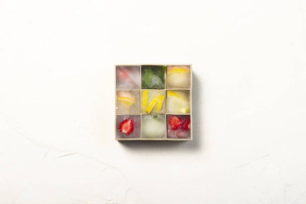 Cubi di ghiaccio con frutta in stampo di silicone su uno sfondo di pietra bianca
 - Foto, immagini