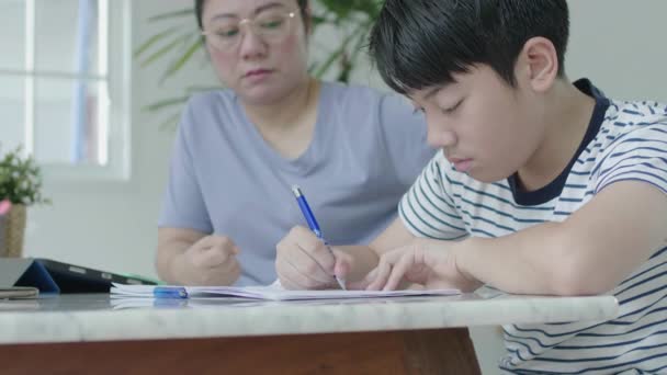 The strict Asian mother is checking the son's education. The son was found guilty of homework. By the mother who cares about the child's learning - Кадры, видео
