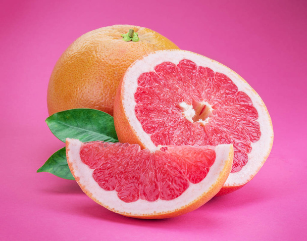 Grapefruits and grapefruit slices isolated on pink background. - Photo, image