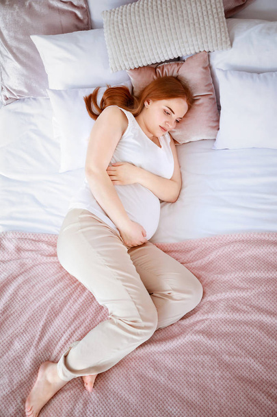 美しい妊娠中の女性のベッドに横になっています。 - 写真・画像