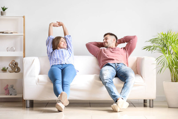 Happy young couple resting together on sofa at home - Foto, imagen