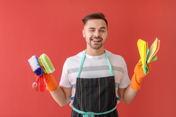 Gelukkige jonge mens met het schoonmaken levering op kleuren achtergrond - Foto, afbeelding