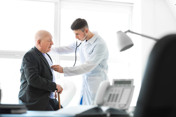 Doctor examining senior man in nursing home - Fotó, kép