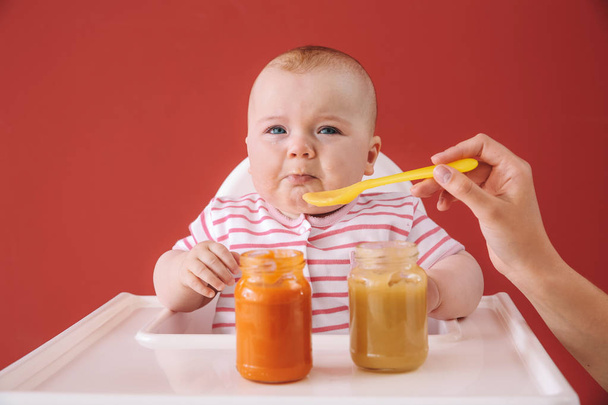 Cute little baby eating food on color background - 写真・画像