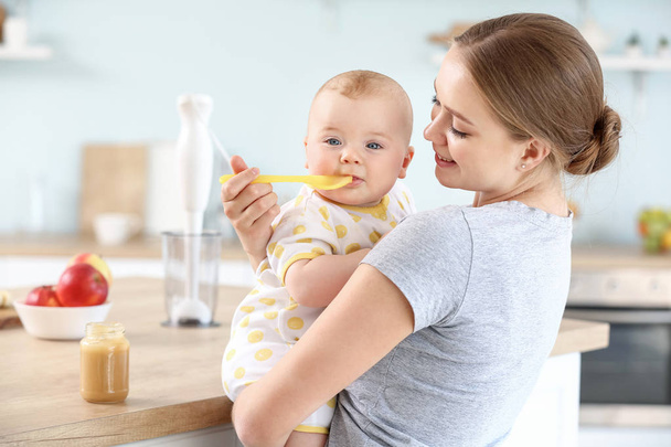 Madre che nutre il suo piccolo bambino in cucina a casa
 - Foto, immagini