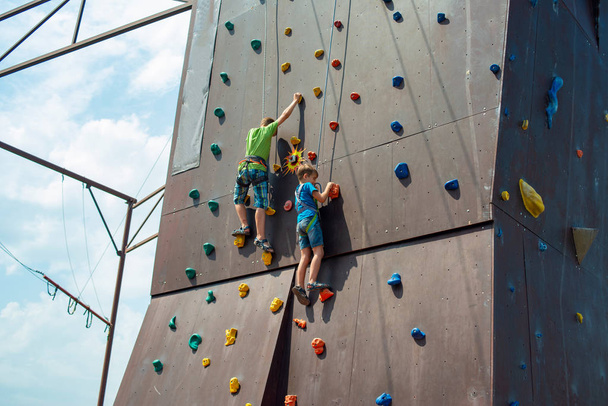 Klettern auf einem künstlichen Aufstieg. Der Junge klettert in einem extremen Park auf die Mauer. - Foto, Bild