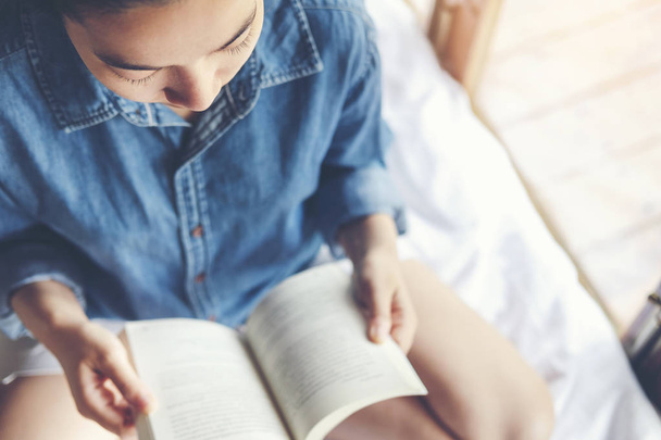 Entspannte Frau liest morgens im Urlaub ein Buch im Bett - Foto, Bild