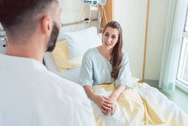 Ο ασθενής περιμένει στο κρεβάτι του νοσοκομείου για να την δει γιατρός. - Φωτογραφία, εικόνα