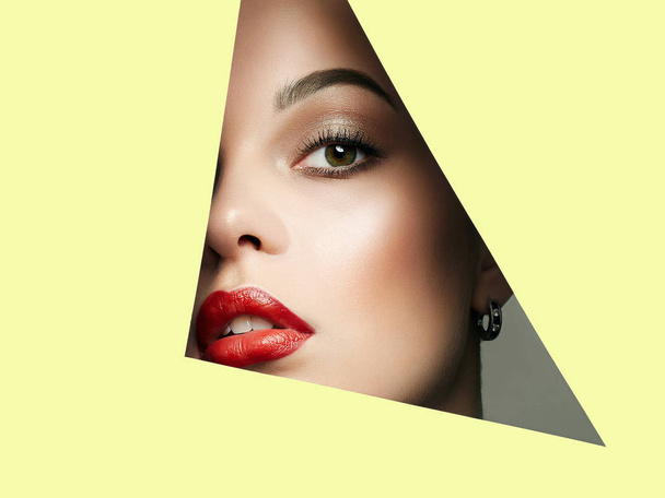 Beautiful red lips woman face  into yellow paper - Photo, Image
