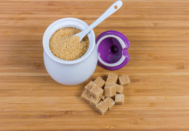 Коричневый сахар в сахарной вазе и коричневые кубики сахара рядом
 - Фото, изображение