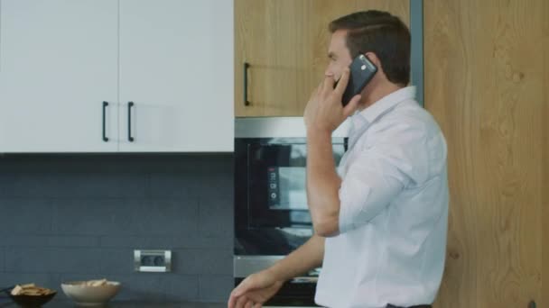 Business man talking cell phone on kitchen. Man having telephone call in house. - Filmmaterial, Video