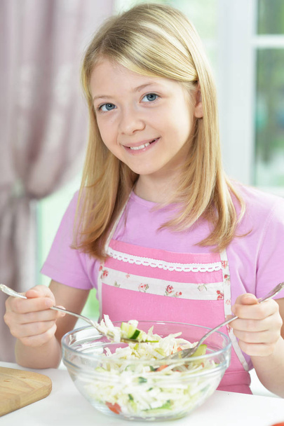 Cute little girl preparing fresh salad on kitchen table  - Valokuva, kuva