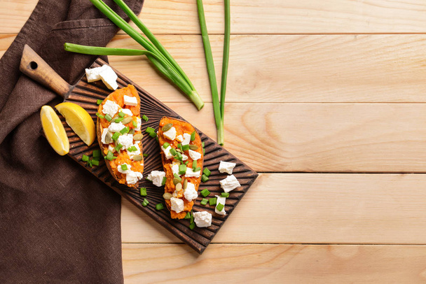 Baked sweet potato with cheese and arugula on wooden background - Foto, immagini