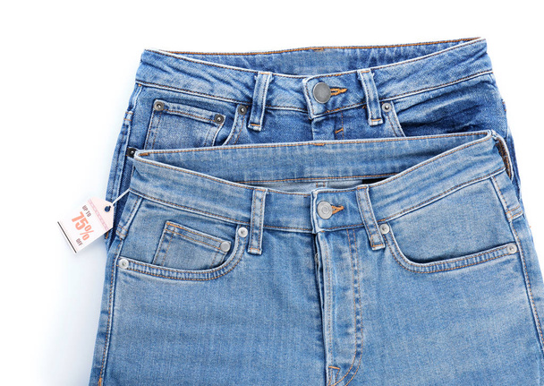 Stylish jeans pants with shopping tag on white background - Foto, Bild