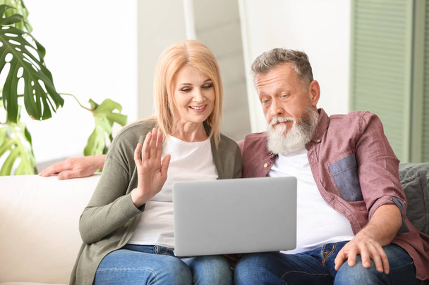 Happy elderly couple with laptop resting at home - Foto, Imagem