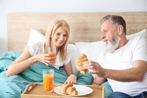 Happy elderly couple having breakfast in bed - 写真・画像