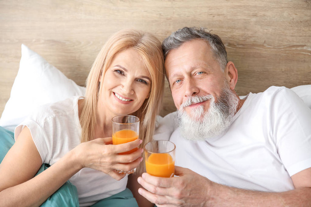Happy elderly couple drinking juice in bed - Valokuva, kuva