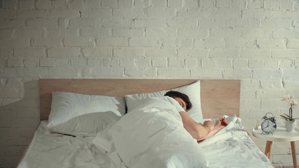 hombre tirando en la cama debajo de la manta, despertando y mirando a su alrededor
 - Metraje, vídeo