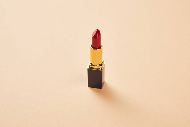 single opened tube of red lipstick on beige - Zdjęcie, obraz