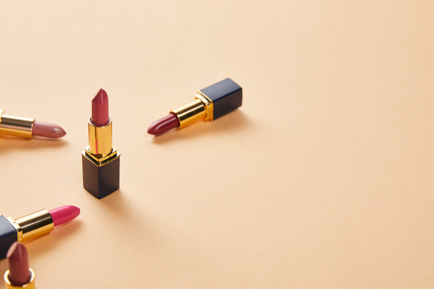 various red shades of lipsticks on beige with copy space - Photo, Image